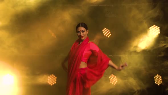 A Young Girl Dancer in a Red Sari. Indian Folk Dance. Shot in a Dark Studio with Smoke and Yellow