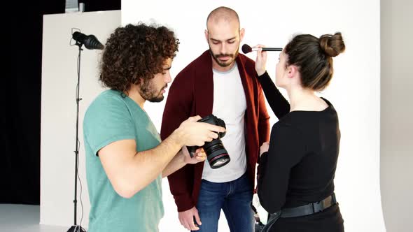 Model getting face make-up while interacting with photographer