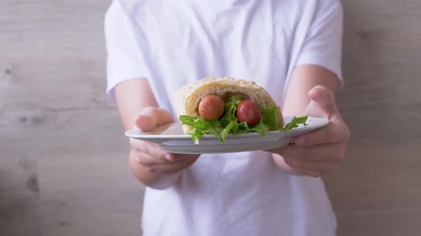 Child Arms Brings Plate Juicy American Hot Dog with Sausages and Lettuce Leaves