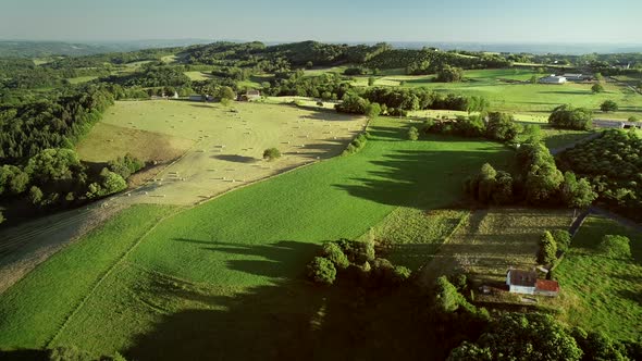 Aerial view of rolling hills and straw bales in field in Correze, France.