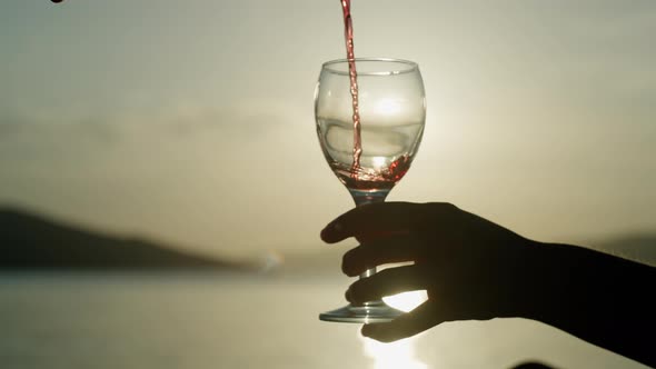 Slow Motion Closeup of Pouring Wine Into a Glass at Sunset By the Ocean