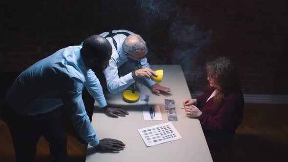 Policemen Interviewing Suspect Woman with Lamp Glowing Into Her Face