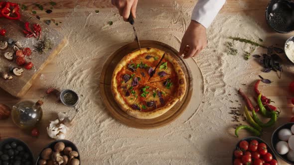 Professional Chef Slicing Pizza By Round Cutter Knife in Restaurant Kitchen