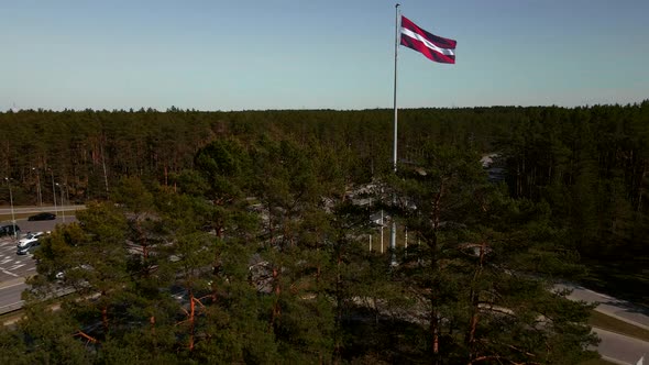 Revealing of National Latvian Flag Behind Trees with Highway in Background