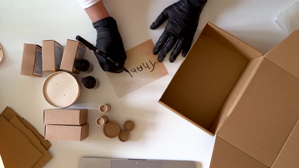 Woman preparing products for shipments writing thank you note