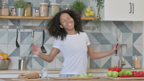 Young African Woman Dancing While Cooking in Kitchen