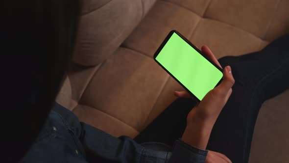 Closeup of Woman Holding Smartphone Chromakey Green Screen Watching Content Sitting on Couch at Home