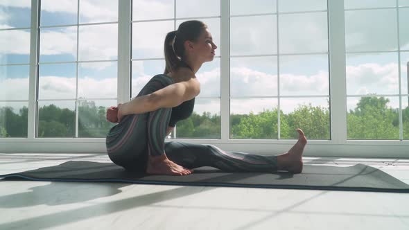 Young Female Doing Yoga in a White Room Filled with Light the Girl Performs Yoga Stands and Muscle