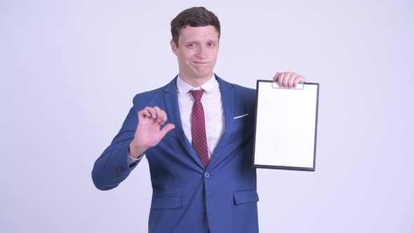 Serious Young Businessman Holding Clipboard and Giving Thumbs Down