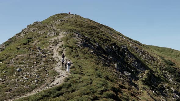 Hikers with backpacks climb to the top of the mountain. Hike to the top. Mountain landscape.