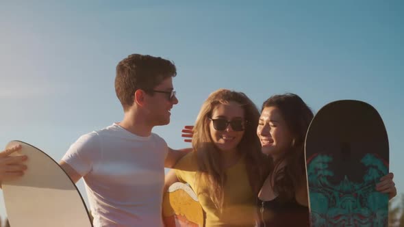 Summer Outdoors. Happy Smiling Friends Giving Five on Sunny Evening Background with Snowboard in