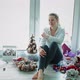 Girl is Sitting By Window Around Her Scattered for Christmas Decorations - VideoHive Item for Sale