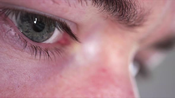 Reflection of screen on person's blue green eye in dark room 1