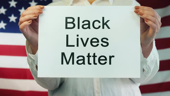 Woman Holds Poster Black Lives Matter on American Flag Background
