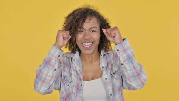 Successful Young African Woman Celebrating on Yellow Background