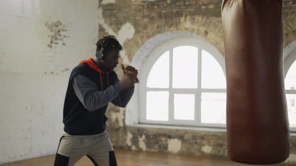 Afro American Male Boxer Practicing Shadow Boxing in Headphones in Bright Hall