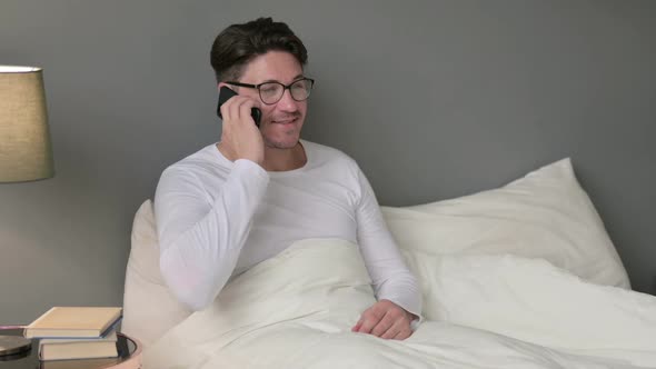 Middle Aged Man Talking on Smartphone in Bed