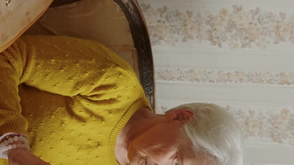 Medium Closeup Vertical Shot of a Caucasian Senior Woman Holding a Book and Thinking