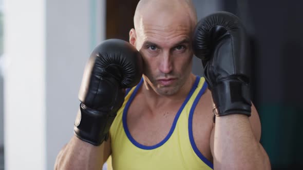 Portrait of caucasian male trainer wearing boxing gloves training at the gym