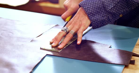 Mid-section of craftswoman cutting leather