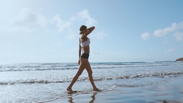 Woman Bare Foot Walking on the Summer Beach. Close Up Leg of Young Woman Walking Along Wave of Sea