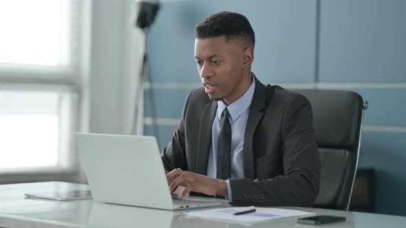 African Businessman Reacting to Loss While using Laptop