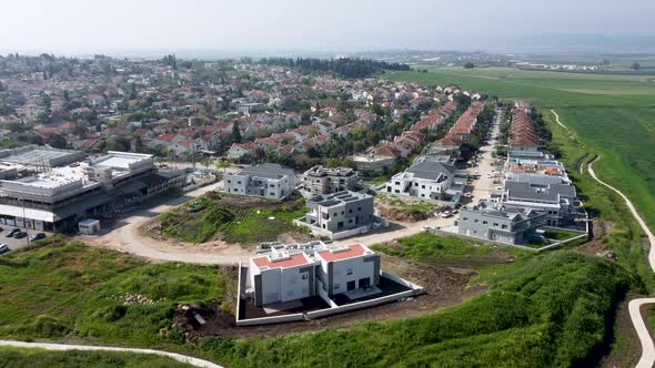 Aerial slow slide drone shot of a new neighborhood near to a green field on a sunny day.