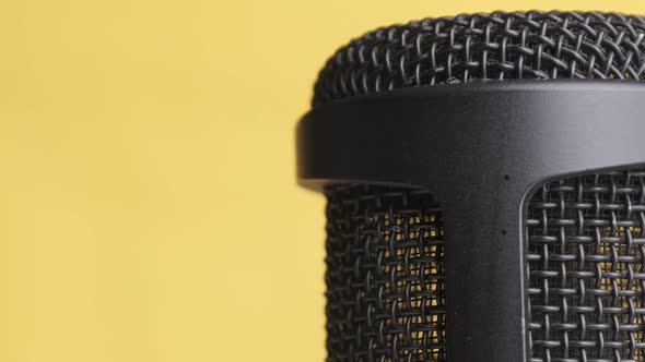 Studio Condenser Microphone Rotates on Yellow Background with Place for Text