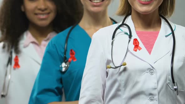 Female Doctors With Red Ribbons Posing for Camera Concept of AIDS Awareness