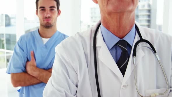 Portrait of male doctors and coworker standing with arms crossed