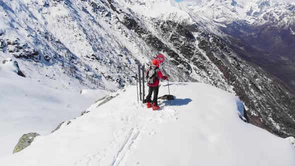 AERIAL: Hiker on mountain top, ski touring mountaineering snow mountain, panoramic view on the alps