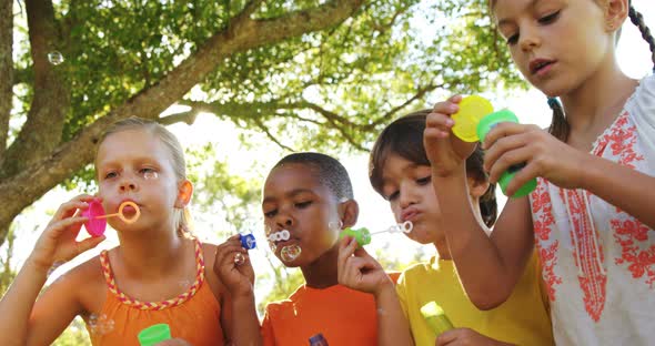 Group of kids blowing bubbles in park