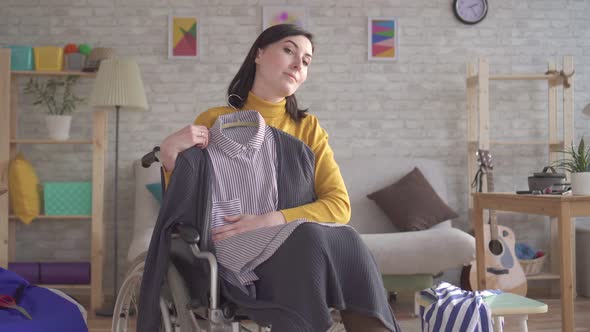 Young Disabled Girl in a Wheelchair Is Going on a Date Trying on Clothes