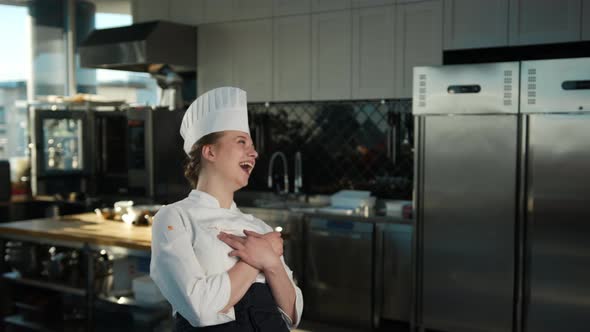 Professional kitchen portrait: Female Chef laughs and dances in the kitchen