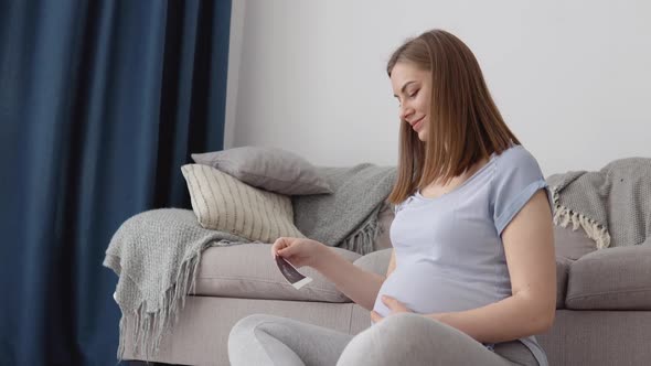 Pregnant Woman Looks at the First Photo of the Fetus of the Unborn Child