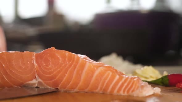 chief cuts the skin off fresh salmon with a sharp knife.