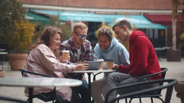 Diverse Group of Happy Friends Using Digital Tablet Drinking Takeaway Coffee at Street Cafe