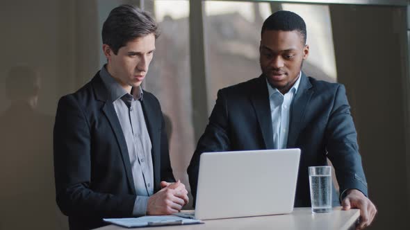 Two Focused Businessmen Multiracial Men Colleagues Look at Laptop Pensive Think About Office Project