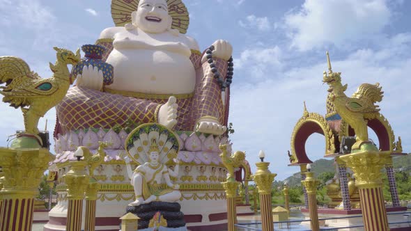 Camera moving away from the Buddha statue at Wat Plai Laem temple in Koh Samui, shot from a low angl