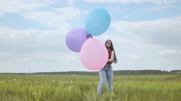 Happy Girl with Big Multicolored Balloons Posing on the Field