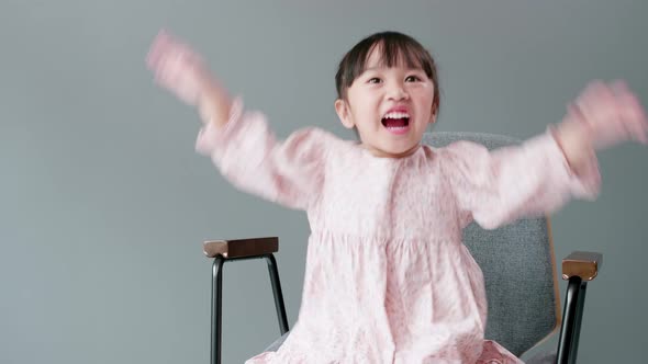 Cheerful and happy child looking at camera and swing arms and pointing to something. Sitting in armc