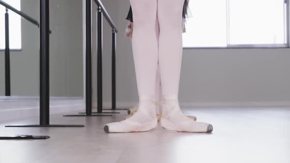 Caucasian ballet female dancers stretching up with a barre before a ballet class