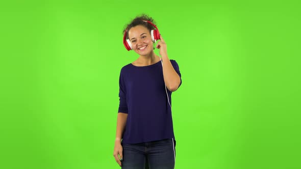 Curly Woman Dancing and Enjoying Music in Big Red Headphones. Green Screen