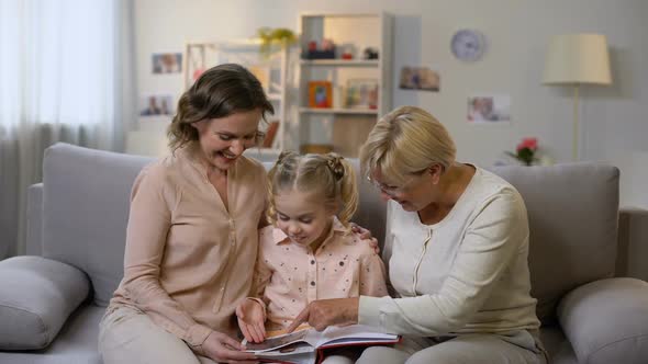 Granny and Mother Showing Photo Album Pictures to Small Girl, Family History