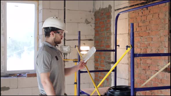 A man builder is studying a construction drawing at a construction site.