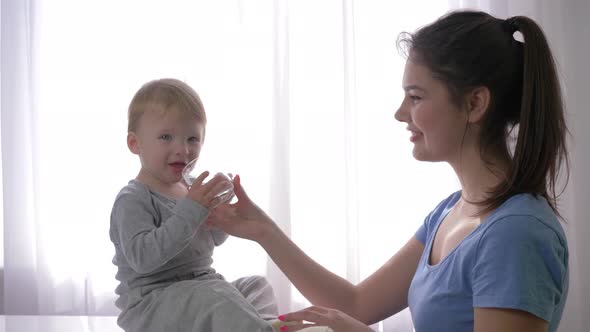 Young Mother Gives Little Son Glass of Mineral Water To Quench Thirst and Baby Is Very Happy and