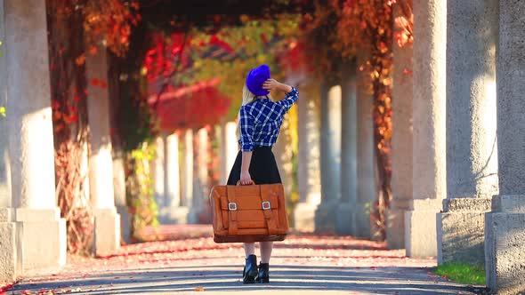 Young girl with suitcase in red ivy alley. Autumn season time