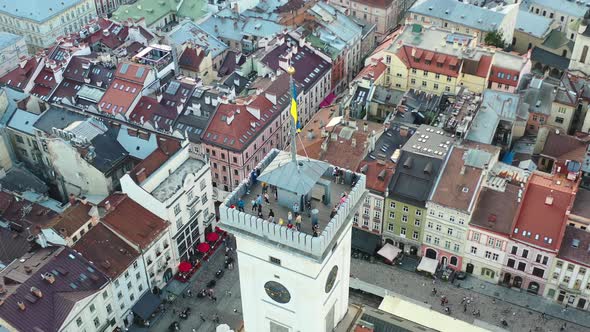 Ukrainian flag waving at the top of a tower in Rynok Square of Lviv Ukraine with European buildings