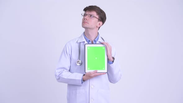 Happy Young Man Doctor Thinking While Showing Digital Tablet