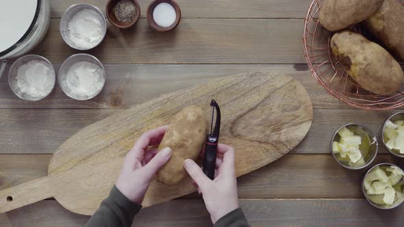 Flat lay. Peeling organic yellow potatoes with potato peeler